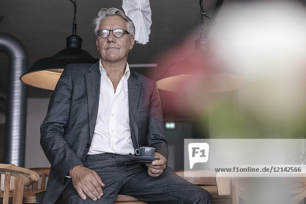 Senior businessman drinking coffee  sitting on table