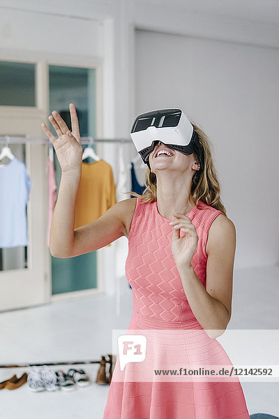 Glückliche junge Frau im Modestudio mit VR-Brille