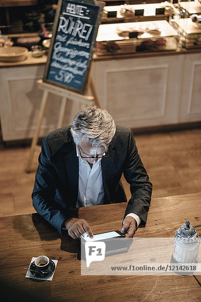 Senior Geschäftsmann sitzend Café  mit digitalem Tablett