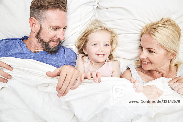 Portrait of happy family lying in bed