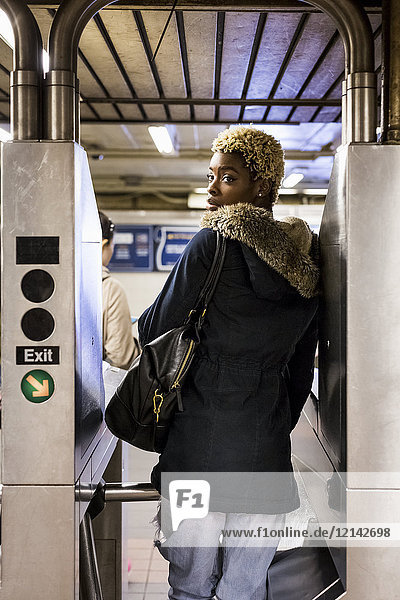 USA  New York City  junge Frau beim Passieren der Barriere in der U-Bahn-Station