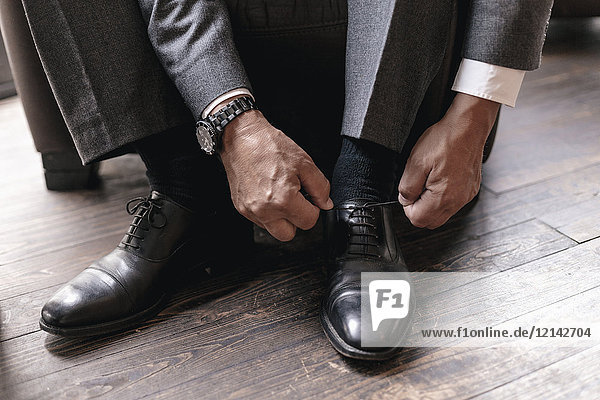 Geschäftsmann beim Anziehen von Schuhen  Schnürsenkelbinden