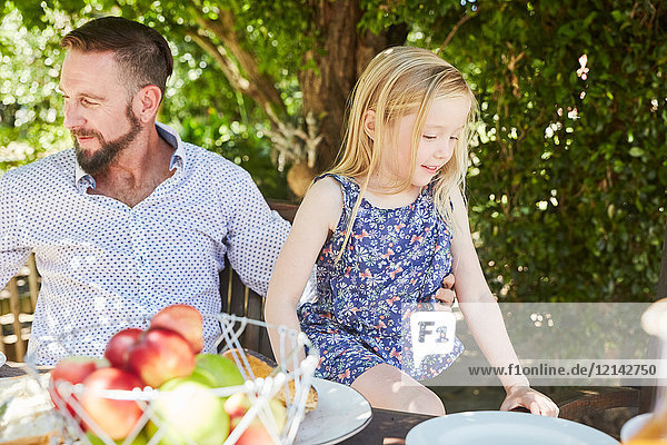 Girl with father sitting at garden table