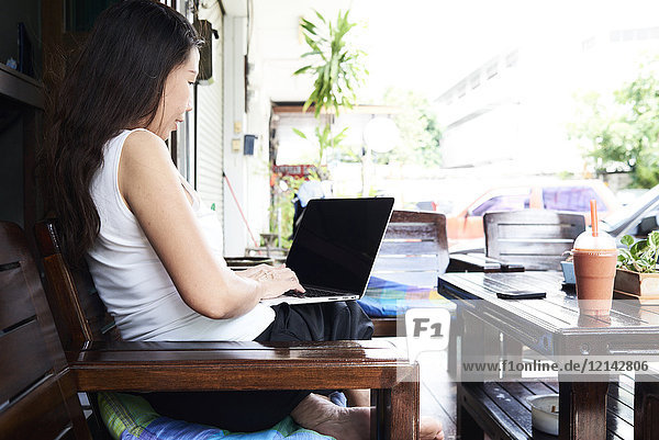 Frau mit Laptop auf Terrassenbank sitzend