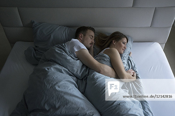 Top view of couple lying in bed at home