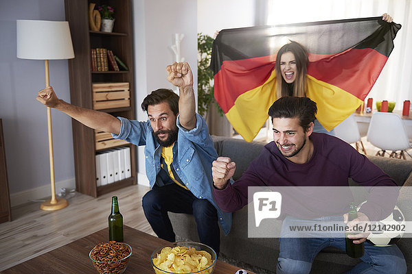 Aufgeregte deutsche Fußballfans beim Fernsehen und Jubeln