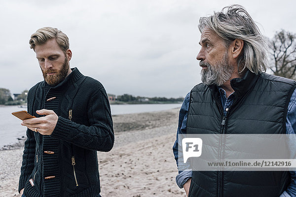 Vater und Sohn treffen sich in der Natur zum Reden Sohn nutzt Smartphone
