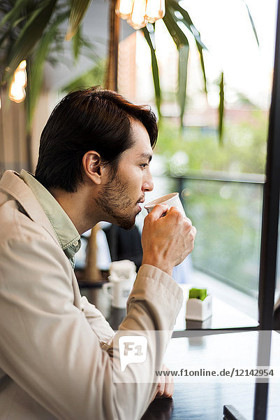 Junger Mann trinkt Kaffee in einem Café
