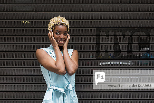 USA  New York  glückliche junge blonde Afroamerikanerin  lächelnd  Hand auf Kopf