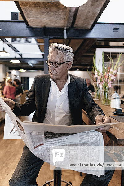 Geschäftsmann sitzt im Café  macht eine Pause und liest Zeitung.