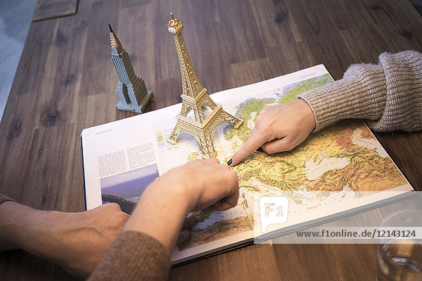 Hands on atlas with model of Eiffel tower and Empire State Building