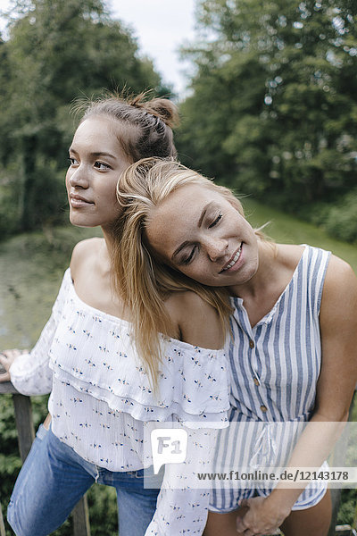 Lächelnde junge Frau ruht auf der Schulter der Freundin