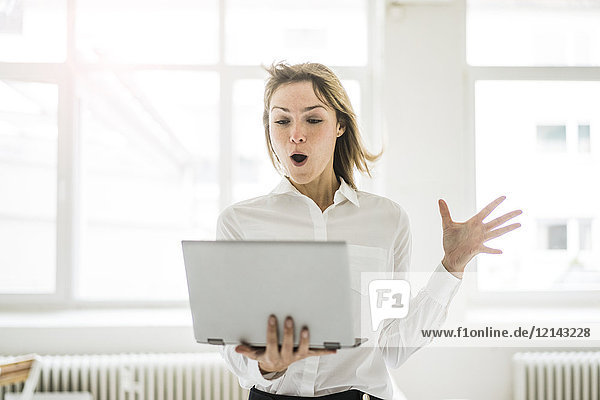 Amazed woman holding laptop