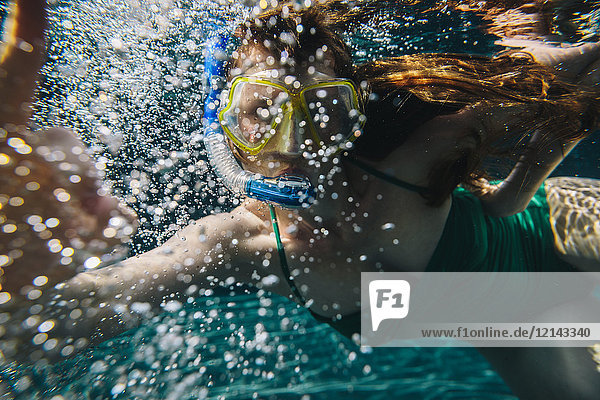 Porträt einer Frau mit Taucherbrille und Schnorchel unter Wasser im Schwimmbad