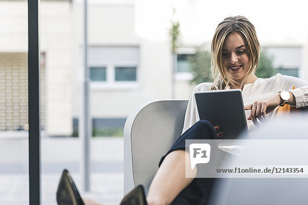 Smiling businesswoman sitting in lounge with tablet