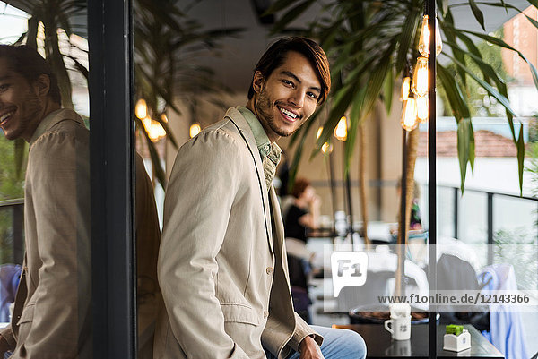 Porträt eines lächelnden jungen Mannes in einem Outdoor-Café
