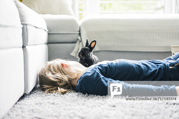 Girl lying with hare in living room