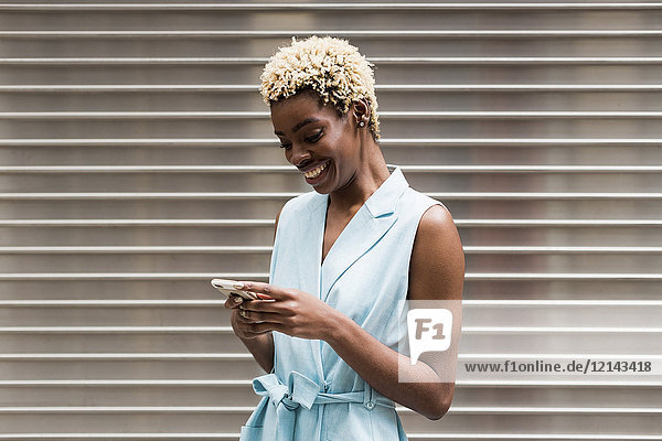 USA  New York  junge blonde Afroamerikanerin mit Smartphone  lächelnd