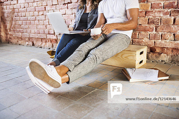 Geschäftsmann und Frau im Loft sitzend  mit Laptop  Gründung eines Start-up-Unternehmens