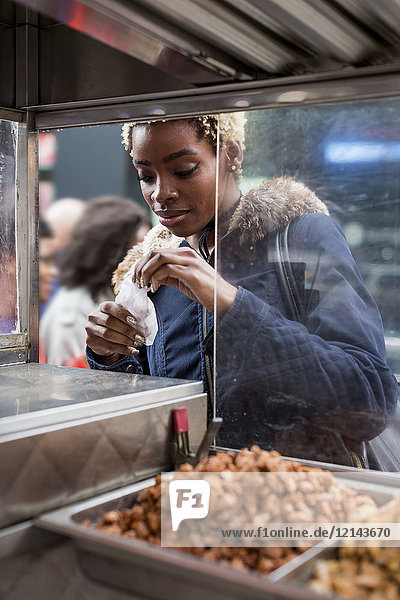 Portrait of young woman buying food on stall