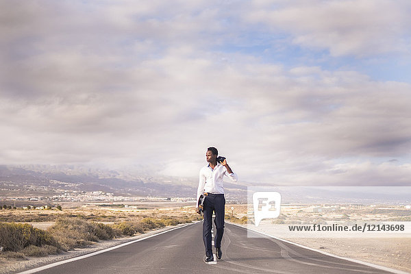 Spain  Tenerife  young businessman with skateboard walking on road