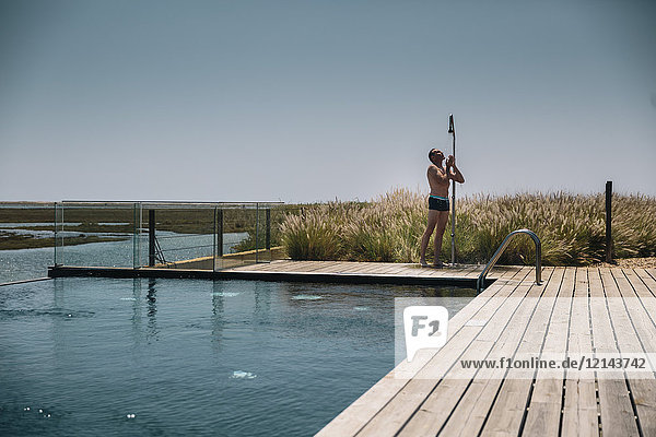 Man taking a shower on the edge of a modern infinity swimming pool