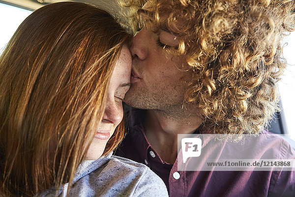 Junges Paar im Auto  junger Mann küsst junges Mädchen