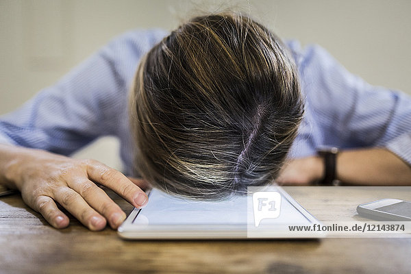 Close-up of woman lying on tablet at desk
