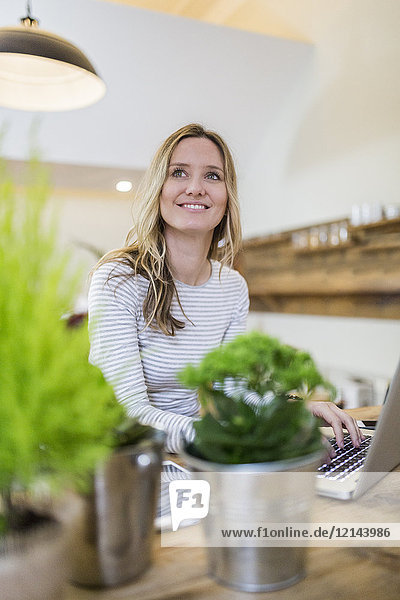 Smiling woman using laptop on wooden table at home