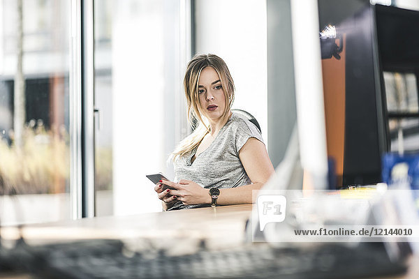 Businesswoman with cell phone at desk in office