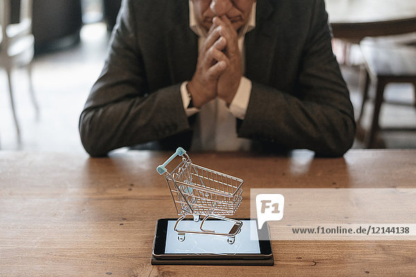 Senior businessman looking at shopping cart on digital tablet
