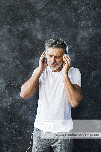 Mature man having fun listening music  wearing headphones