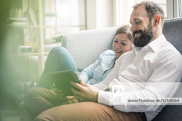 Smiling couple using tablet on couch