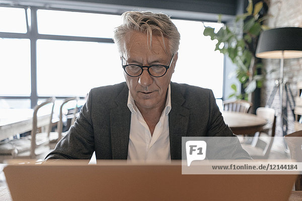 Senior Geschäftsmann sitzend in einem Café  mit Laptop