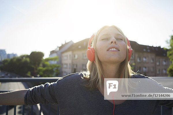 Portrait einer jungen Frau mit geschlossenen Augen Musik hören mit Kopfhörer