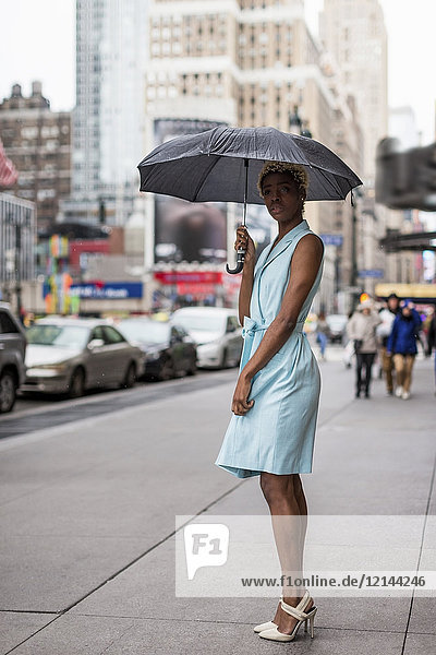 USA  New York  junge blonde Afroamerikanerin mit Regenschirm