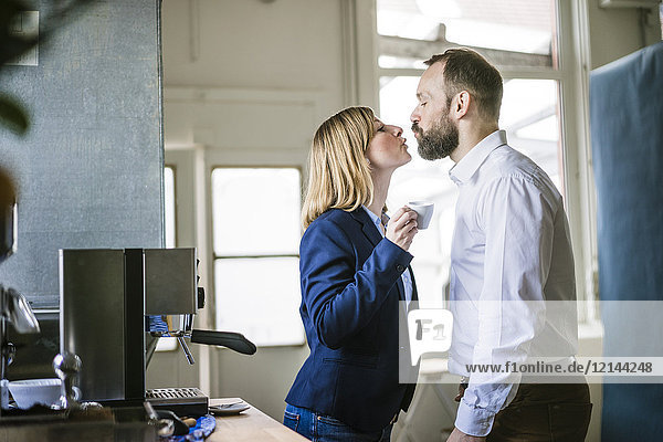 Businessman kissing businesswoman in office