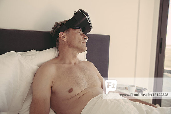 Müde Mann mit VR-Brille im Bett