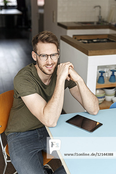 Portrait of smiling man with tablet in kitchen at home