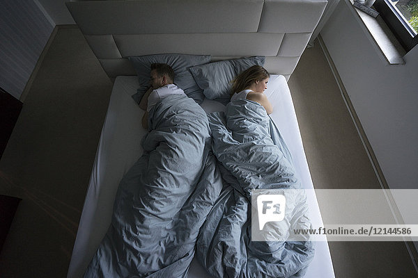 Top view of couple lying in bed at home