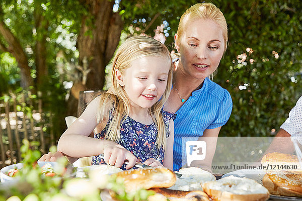 Girl with mother having breakfast at garden table
