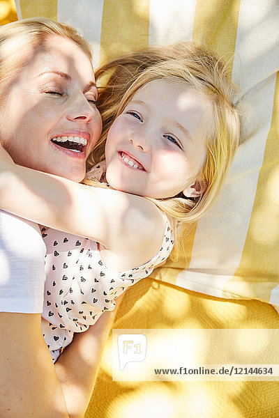 Fröhliches Mädchen und Mutter umarmend auf einer Decke