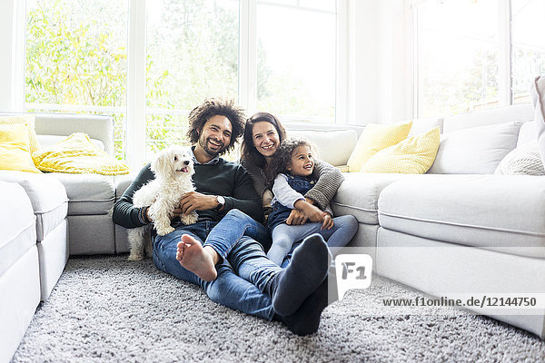 Fröhliche Familie mit Hund im gemütlichen Wohnzimmer