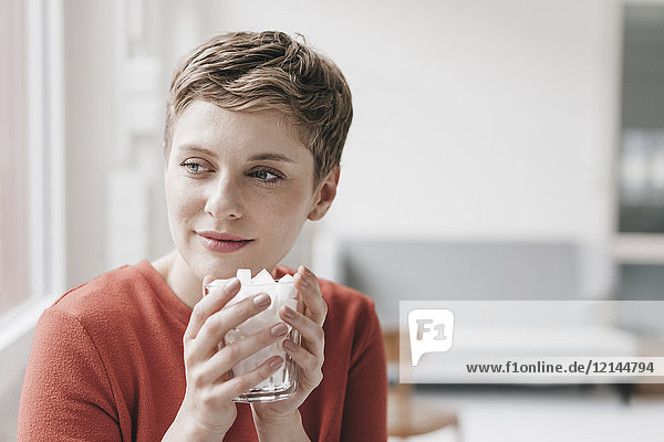 Lächelnde Frau hält Glas voll mit Zuckerwürfeln