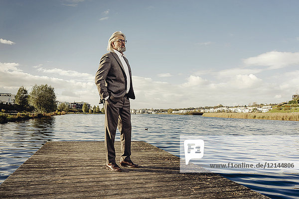 Älterer Mann auf einem Steg am See.