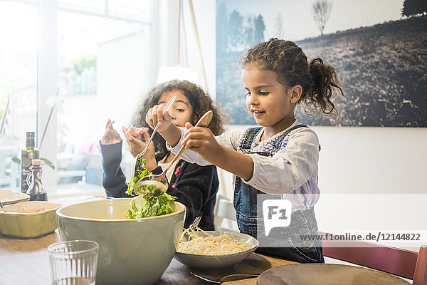 Glückliche Familie isst Spaghetti  Mädchen serviert Salat