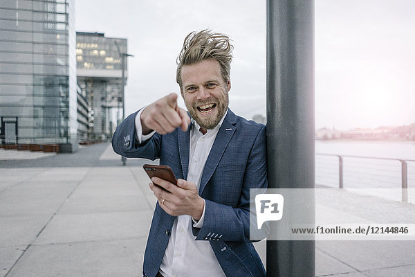 Portrait of happy businessman with cell phone in the city