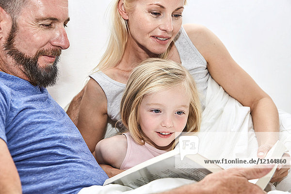 Happy family in bed reading book together