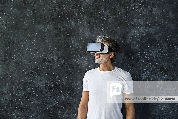Mature man looking through VR glasses