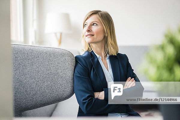 Smiling businesswoman sitting on couch in office lounge